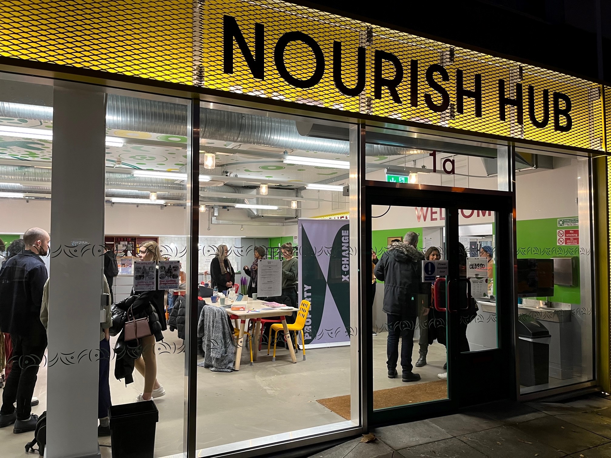 View of Nourish Hub from the outside looking in at night.